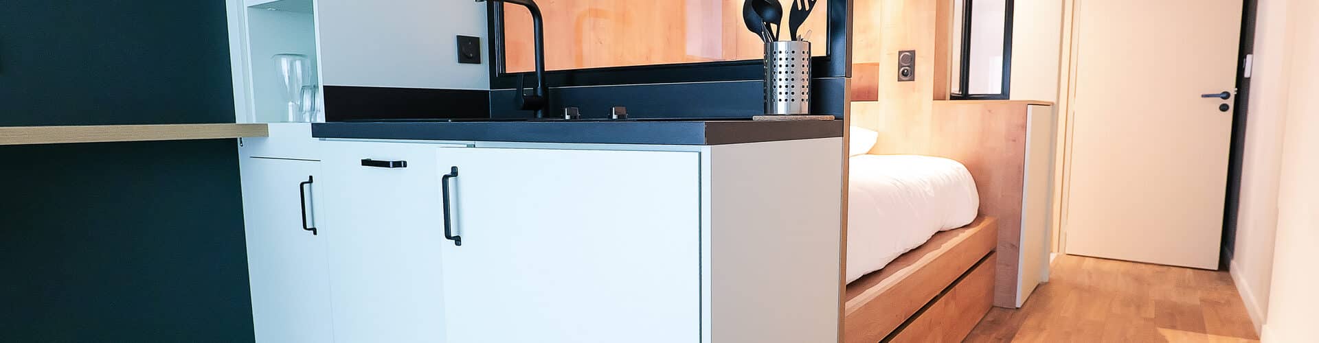 Modern furnished studio at Whoo Residence Rennes Gare, featuring a smartly designed interior with a functional kitchen and cozy sleeping area.